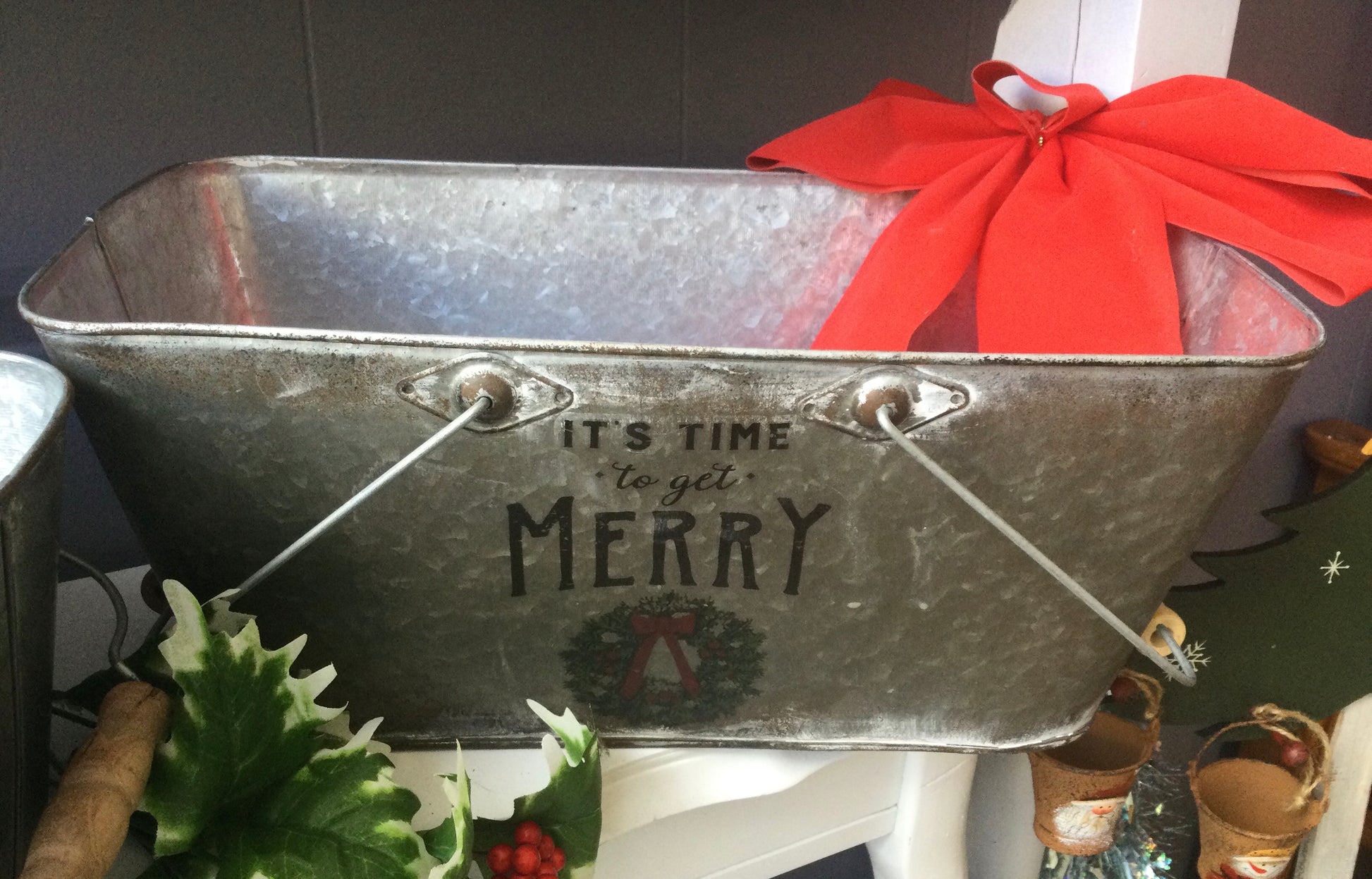 Rounded rectangle tin planter with wood handles. Red typography  “It’s Time to get Merry” 